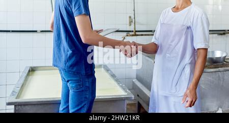 Im contento di essere parte di questo. Scatto corto di due persone che agita le mani in una fabbrica di formaggio. Foto Stock