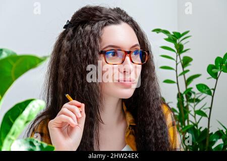 Primo piano ritratto bella donna pensierosa in occhiali guarda via sul posto di lavoro. Donna che lavora a casa Foto Stock