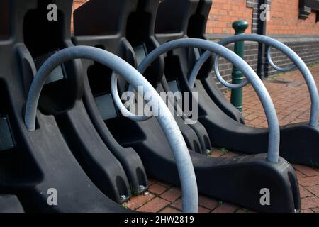 primo piano della struttura di parcheggio ciclabile, barre metalliche circolari con meccanismo di bloccaggio per fissare le biciclette per il pubblico contro un muro di mattoni rossi in una città sono Foto Stock