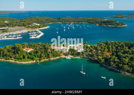 Foreste della penisola con dintorni di Rovigno. Tetti rossi di vecchi edifici nella città croata vicino al mare Adriatico alla luce del sole. Panorama aereo Foto Stock