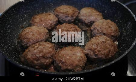 Le cotolette di carne vengono fritte in padella. Concetto. Succose e deliziose cotolette di carne vengono fritte in olio su una padella nera. Semplici e deliziose cotolette di carne. Semplice casa coo Foto Stock