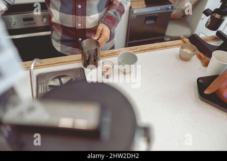 Foto del barista maschio che tiene la caraffa con il latte Foto Stock