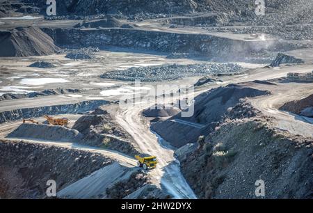 Macchine di perforazione e frantumazione e dumper da miniera che lavorano in cave di pietra, vista dall'alto Foto Stock