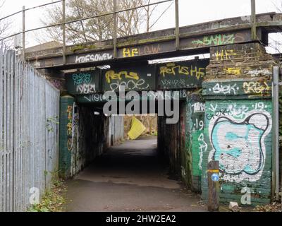 LONDRA, INGHILTERRA - FEBBRAIO 20 2022: Ambiente urbano, vecchio sottopassaggio scruffy con graffiti e recinzione rotta oltre. Foto Stock