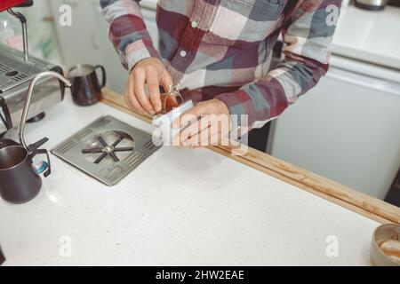 Primo piano delle mani maschili del barista che prepara il caffè Foto Stock