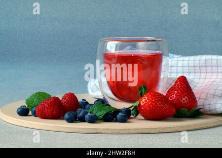 sul tavolo ci sono fragole fresche, lamponi e mirtilli e gelatina di frutti di bosco in un bicchiere trasparente Foto Stock