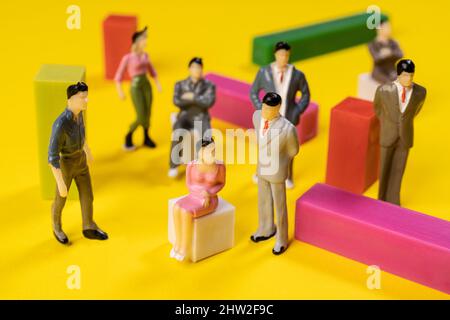 alcune persone in miniatura in relazione l'una all'altra su una superficie colorata Foto Stock