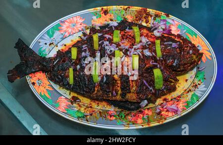 Pesce alla griglia, orata di mare con aggiunta di spezie, erbe e limone sul piatto della griglia. Foto Stock