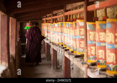 Monaco buddista locale dal Tibet e del patrimonio tibetano usando l'uso della ruota di preghiera / ruota decorata e dipinta ruote di preghiera / girare una ruota per pregare, a Langmusi, Cina. PRC. Langmusi si trova ai margini dell'altopiano tibetano. (125) Foto Stock