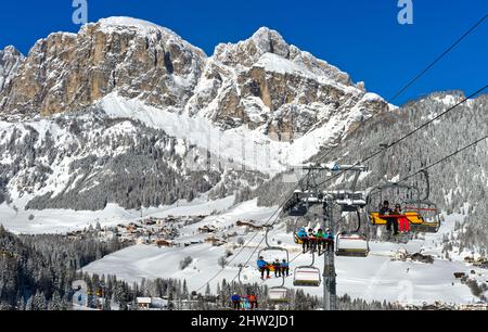 Sciatori in seggiovia nel comprensorio sciistico di la Villa, Dolomiti, Alto Adige, Italia Foto Stock