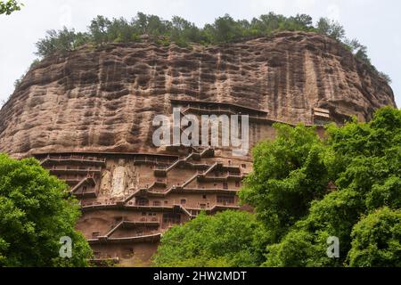 Gradini e passerelle attaccati al fronte roccioso consentono ai visitatori di vedere le antiche statue di argilla di Buddha e divinità buddiste statua attaccata e scolpita nella superficie di pietra della faccia di roccia. Le Grotte di Maijishan, precedentemente romanizzate come Maichishan, Sono una serie di 194 grotte tagliate sul lato della collina di Majishan a Tianshui, provincia di Gansu, Cina PRC. (67/125) Foto Stock