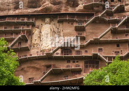 Gradini e passerelle attaccati al fronte roccioso consentono ai visitatori di vedere le antiche statue di argilla di Buddha e divinità buddiste statua attaccata e scolpita nella superficie di pietra della faccia di roccia. Le Grotte di Maijishan, precedentemente romanizzate come Maichishan, Sono una serie di 194 grotte tagliate sul lato della collina di Majishan a Tianshui, provincia di Gansu, Cina PRC. (67/125) Foto Stock