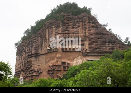 Gradini e passerelle attaccati al fronte roccioso consentono ai visitatori di vedere le antiche statue di argilla di Buddha e divinità buddiste statua attaccata e scolpita nella superficie di pietra della faccia di roccia. Le Grotte di Maijishan, precedentemente romanizzate come Maichishan, Sono una serie di 194 grotte tagliate sul lato della collina di Majishan a Tianshui, provincia di Gansu, Cina PRC. (67/125) Foto Stock