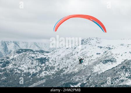 Splendida vista di un Parapendio su montagne innevate e chiare con un cielo chiaro Foto Stock