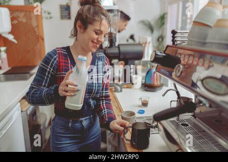 Barista signora sorridente che prepara il caffè in un caffè Foto Stock