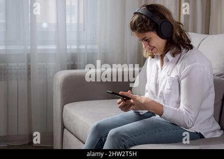 Donna con disabilità in cuffie ascolta musica in attesa telefono Foto Stock