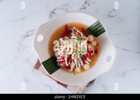 Calamari al vapore con aglio e lime in un piatto isolato sul tappeto vista dall'alto su sfondo di marmo grigio Foto Stock