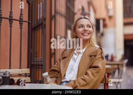 Ritratto di donna sorridente seduto al tavolo del caffè di strada Foto Stock
