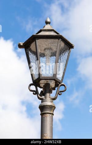 Inquadratura ad angolo basso di una luce di una lanterna stradale con cielo blu e nuvole Foto Stock