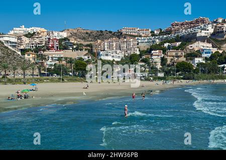 Persone che prendono il sole con i loro ombrelloni sulla sabbia e fanno il bagno nella Platja de l'Illa della città costiera di Cullera, provincia di Valencia, Spagna; Foto Stock