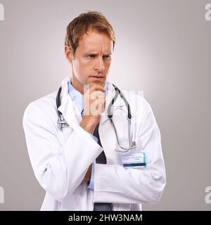 Riflettere sulla sua prossima procedura. Studio girato di un bel medico guardando premuroso. Foto Stock