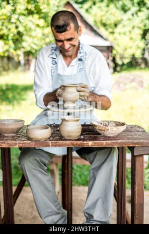 Sibiu City, Romania - 26 luglio 2019. Mani di un vasaio che forma una pentola di argilla sulla ruota di un vasaio alla fiera dei vasai da Sibiu, Romania Foto Stock