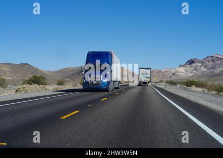 Nevada: I semi-camion vengono mostrati guidare su un'autostrada a due corsie vicino alla città di Beatty, nello stato del Nevada. Foto Stock