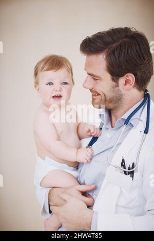 Non è semplicemente adorabile. Un pediatra maschio che tiene un paziente tra le braccia. Foto Stock