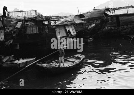 Vita nel 1960s coloniale Hong Kong, con una popolazione in rapida crescita di oltre 4 milioni di persone, molti sono costretti a vivere in baraccopoli e baraccopoli, nella foto di gennaio 1968. I nostri spettacoli di foto ... I bambini si spostano tra i Sampans, barche cinesi in legno a fondo piatto. Alcuni sampani includono un piccolo rifugio a bordo e possono essere utilizzati come abitazione permanente nelle acque interne. Foto Stock