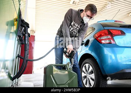 03 marzo 2022, Austria, Hörbranz: Anselm Stahl di Friedrichshafen riempie un barattolo supplementare presso la stazione di servizio di Schindele. Si trova a poche centinaia di metri da Lindau in Germania. La guerra in Ucraina sta spingendo i prezzi delle pompe di gas tedesche ai massimi storici. Per alcuni automobilisti del sud, un paese vicino in particolare sembra come il Land promesso in confronto, motivo per cui la corsa alle stazioni di benzina al confine è probabile aumentare. Foto: Felix Kästle/dpa Foto Stock