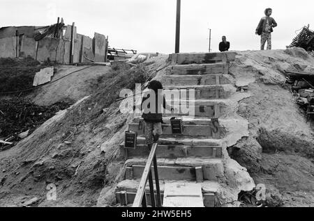 Vita nel 1960s coloniale Hong Kong, con una popolazione in rapida crescita di oltre 4 milioni di persone, molti sono costretti a vivere in baraccopoli e baraccopoli, nella foto di gennaio 1968. I nostri spettacoli di foto ... Bambino che fa il viaggio quotidiano per raccogliere l'acqua preziosa dal fiume. Foto Stock