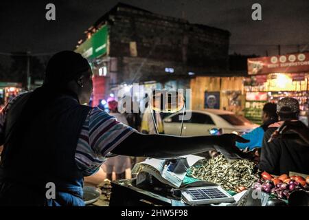 Un venditore di strada che utilizza una lampada solare fornendo al contempo servizi ai suoi clienti per le strade nelle baraccopoli di Kibera, Nairobi. Migliaia di famiglie in K. Foto Stock