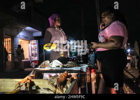 Un venditore di strada che utilizza una lampada solare fornendo al contempo servizi ai suoi clienti per le strade nelle baraccopoli di Kibera, Nairobi. Migliaia di famiglie in K. Foto Stock