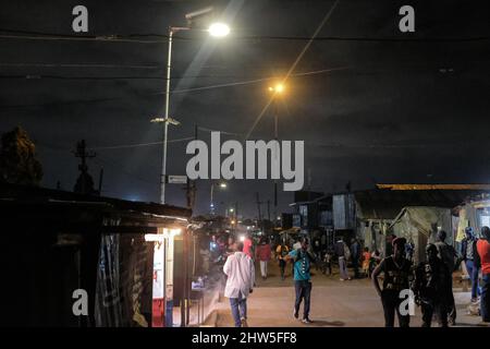 I residenti locali tornano a casa passando le luci di strada a energia solare della comunità nelle baraccopoli di Kibera. Migliaia di famiglie nelle baraccopoli Kibera del Kenya dipendono o Foto Stock