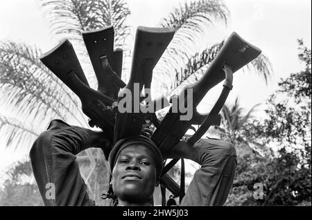 Un soldato Biafran visto qui in possesso di una selezione di armi durante il conflitto Biafran, 11th giugno 1968. La guerra civile nigeriana, nota anche come guerra di Biafran, è durata due anni e mezzo, dal 6 luglio 1967 al 15 gennaio 1970, ed è stata combattuta per contrastare la secessione di Biafra dalla Nigeria. Il popolo indigeno Igbo di Biafra sentì di non poter più coesistere con il governo federale dominato dal nord a seguito dell'indipendenza dalla Gran Bretagna. Le tensioni politiche, economiche, etniche, culturali e religiose si sono infine trasformate in una guerra civile dopo il colpo di stato militare del 1966, poi contro-co Foto Stock