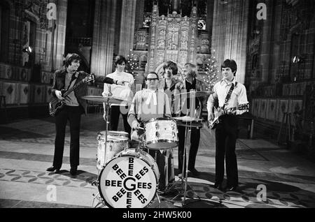 I Bee Gees si esibiscono presso la cattedrale anglicana di Liverpool. I Bee Gees sono i fratelli Maurice, Barry e Robin Gib, Colin Peterson e vince Malouney. Il decano di Liverpool, il Rev. Edward Patey non poteva resistere a provare i tamburi. 14th dicembre 1967. Foto Stock