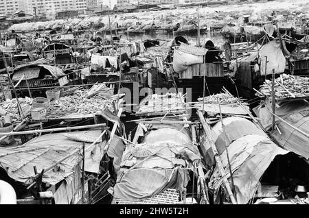 Vita nel 1960s coloniale Hong Kong, con una popolazione in rapida crescita di oltre 4 milioni di persone, molti sono costretti a vivere in baraccopoli e baraccopoli, nella foto di gennaio 1968. I nostri spettacoli di foto ... Sampans, barche cinesi a fondo piatto. Alcuni sampani includono un piccolo rifugio a bordo e possono essere utilizzati come abitazione permanente nelle acque interne. Foto Stock