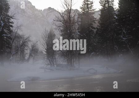 La valle di Yosemite è circondata da un sottile strato di nebbia che si estende sul fiume merced, fornendo un'atmosfera inquietante intorno al tramonto. Foto Stock