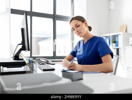 medico o infermiere con appunti di lavoro in ospedale Foto Stock