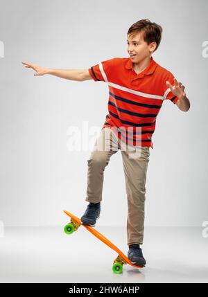 ragazzo sorridente che cavalca su skateboard corto Foto Stock