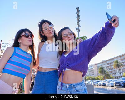 Tre amici con abiti vintage che prendono un selfie con la mobile all'aperto Foto Stock