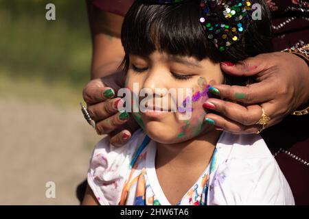 Tema festivo indiano - ragazza felice asiatica del bambino che ha divertimento con la polvere non tossica del colore dell'Holi dell'erbe chiamata Gulal o Abir Rang Aber Foto Stock