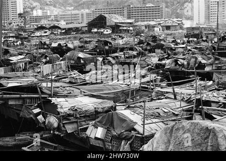 Vita nel 1960s coloniale Hong Kong, con una popolazione in rapida crescita di oltre 4 milioni di persone, molti sono costretti a vivere in baraccopoli e baraccopoli, nella foto di gennaio 1968. I nostri spettacoli di foto ... Sampans, barche cinesi a fondo piatto. Alcuni sampans includono un piccolo rifugio a bordo e può essere utilizzato come abitazione permanente sulle acque interne, nuovi blocchi di reinsediamento alto sullo sfondo. Foto Stock