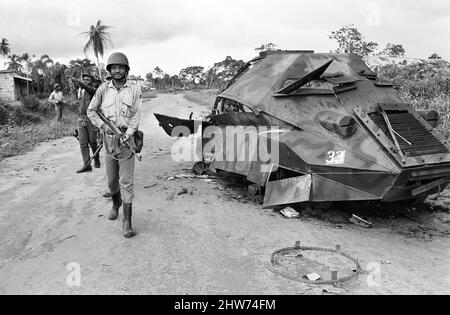 Un soldato Biafran visto qui accanto ad un esercito nigeriano distrutto corazzato portaerei durante il conflitto. 11th giugno 1968 la guerra civile nigeriana, nota anche come guerra di Biafran, durò due anni e mezzo, dal 6 luglio 1967 al 15 gennaio 1970, e fu combattuta per contrastare la secessione di Biafra dalla Nigeria. Il popolo indigeno Igbo di Biafra sentì di non poter più coesistere con il governo federale dominato dal nord a seguito dell'indipendenza dalla Gran Bretagna. Le tensioni politiche, economiche, etniche, culturali e religiose si sono infine follate nella guerra civile dopo i militari del 1966 Foto Stock