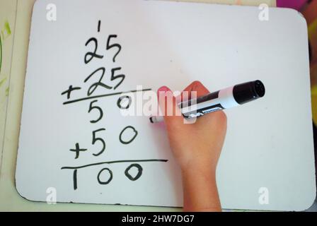 Seconda ragazza di grado imparando come portare quella sopra una lavagna bianca mentre l'apprendimento a distanza non è la matematica di nucleo comune Foto Stock