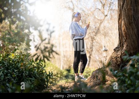 Giovane donna che fa sport e ascolta musica nel parco Foto Stock
