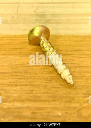 Metallo color oro avvitare su un banco di legno da vicino. Foto di alta qualità Foto Stock