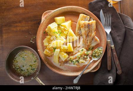 Piatto di pesce - filetto di merluzzo fritto con patate bollite su tavola di legno. Cucina mediterranea con filetto di pesce Foto Stock