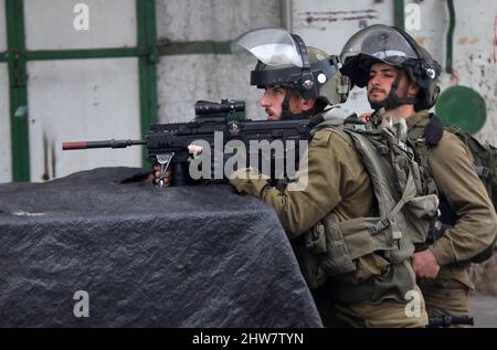 Hebron. 4th Mar 2022. Un soldato israeliano punta la sua arma contro i manifestanti palestinesi durante gli scontri a seguito di una protesta contro l'espansione degli insediamenti ebraici nella città di Hebron, in Cisgiordania, il 4 marzo 2022. Credit: Mamoun Wazwaz/Xinhua/Alamy Live News Foto Stock