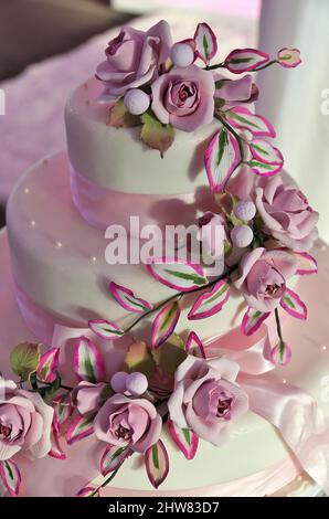 Elegante torta di nozze bianca avvolta in squisito fondente e Rose Marzipan e nastro rosa velato Foto Stock